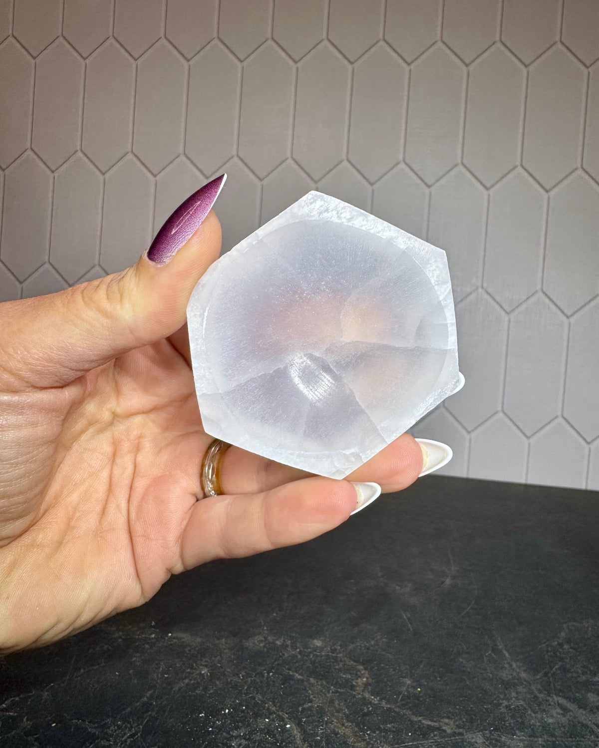 Hand holding a white selenite hexagon bowl for scale