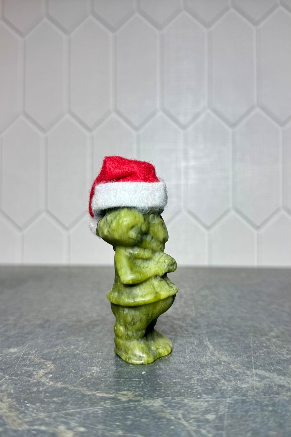 Large green jade Grinch carving with Santa hat, side view